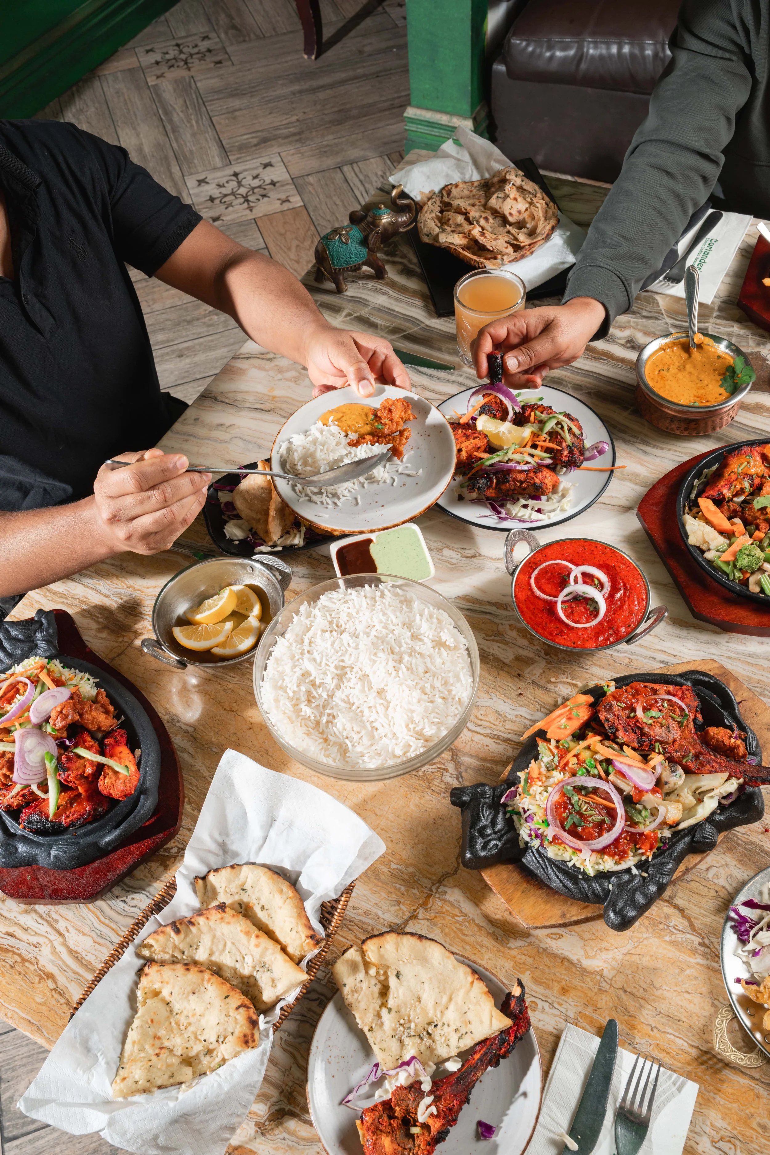 A shared table of Coriander's curries, naan and rice